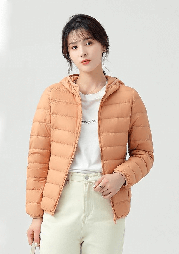 Woman wearing a stylish, ultralight down jacket with hood, ideal for outdoor activities, offering warmth and windproof protection.